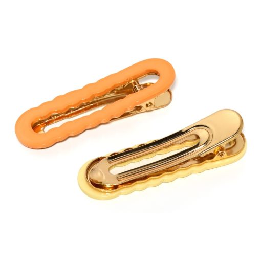Zwei stylische Haarklammern, eine in Orange und eine in Gold, auf weißem Hintergrund.