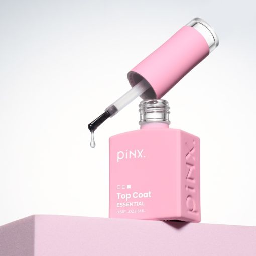 Nahaufnahme eines rosa piNX Top Coat Essential Nagellacks mit Pinsel und Tropfen